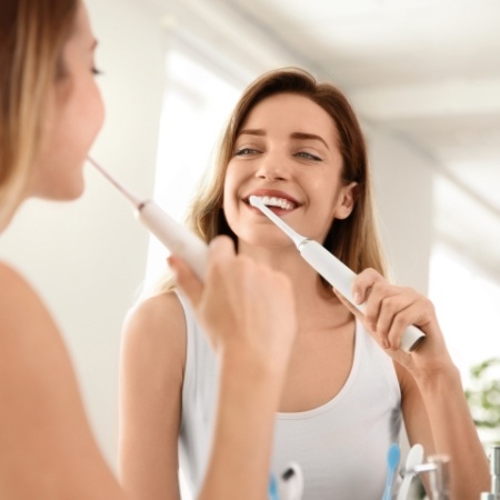 Woman brushing teeth to prevent dental emergencies