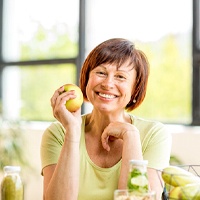 woman sitting at kitchen table and holding apple