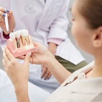 Dentist showing patient model of dental implant in White Plains