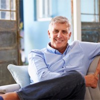 Man with dental implants in White Plains smiling on couch