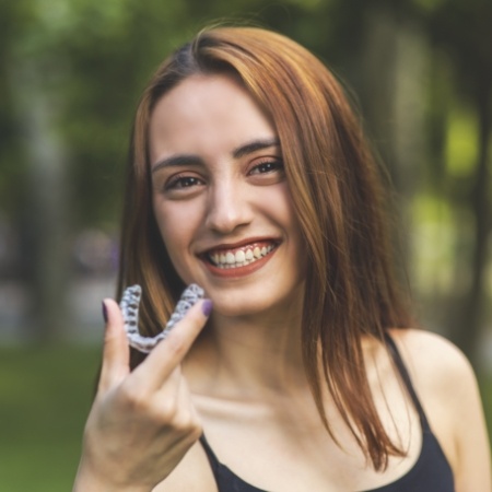 Smiling woman holding an invisalign tray