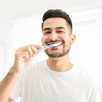 Closeup of man in white shirt brushing his teeth