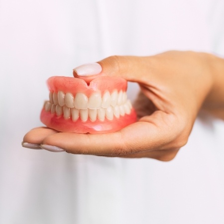 Hand holding full set of dentures